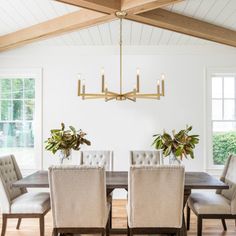 a dining room table with chairs and a chandelier hanging from the ceiling over it