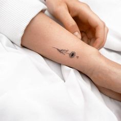 a woman's arm with a dandelion tattoo on the left side of her arm