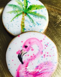 two decorated cookies with palm trees and flamingos on them are sitting on a table