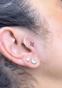 a woman with piercings on her ear and behind the ear is a small flower