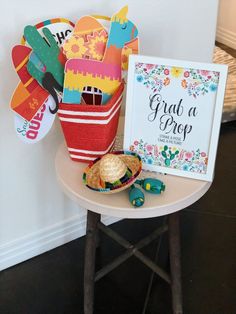 a small table with a sign and hat on it next to a basket full of hats