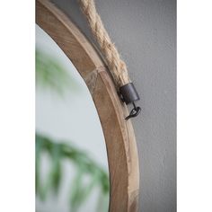 a mirror hanging on the side of a wall with a rope attached to it's edge