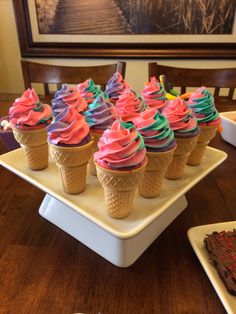 cupcakes with colorful frosting and sprinkles on a tray next to a slice of chocolate cake