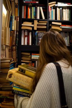 a woman standing in front of a bookshelf filled with lots of different types of books