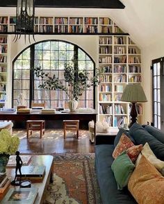 a living room filled with lots of furniture and bookshelves full of books on top of them