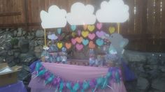 a table topped with lots of candy and balloons in the shape of heart shaped clouds