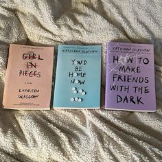 three books laying on top of a bed next to each other with writing on them