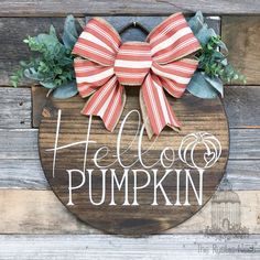 a wooden sign that says hello pumpkin with a bow on it's front door