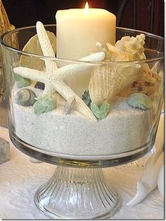 a glass bowl filled with sand and seashells