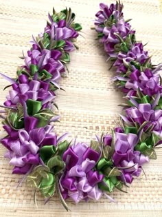 a wreath made out of purple flowers on top of a woven tablecloth with green leaves