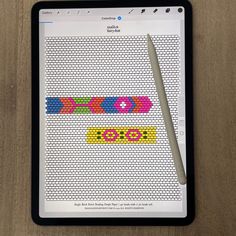 a tablet with a cross stitch pattern on the screen and a pen next to it