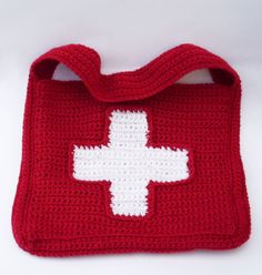 a crocheted bag with a white cross on the front in red and white