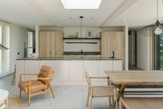 an open kitchen and dining room with skylights above the countertop, along with wooden chairs