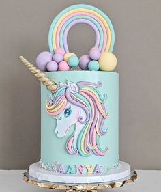 there is a cake decorated with an unicorn on the front and rainbow decorations on the back