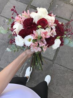 a person holding a bouquet of flowers on the ground