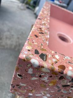 a close up of a pink sink with rocks on the outside and in between it's sides