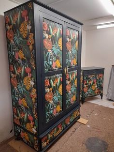 an armoire painted with colorful flowers and leaves on it's sides, sitting in the middle of a room