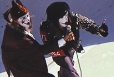 two people with painted faces and makeup are on skis in front of a ramp