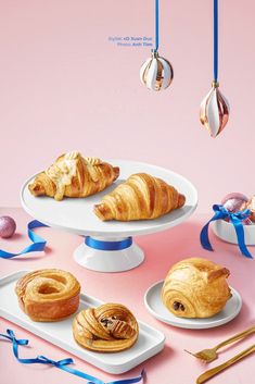 there are many different pastries on the trays with blue ribbons around them and one has a croissant in it