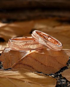 two wedding rings sitting on top of leaves