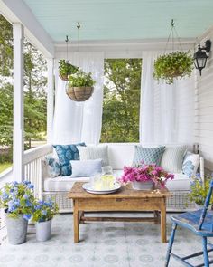 the porch is decorated with blue and white furniture, potted plants, and flowers