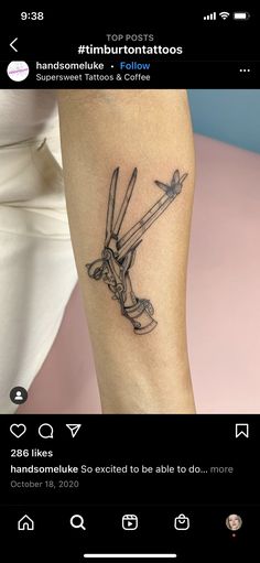 a tattoo on the arm of a woman with scissors in her hand and an arrow