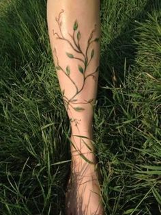 a woman's foot with leaves on it and grass in the foreground behind her