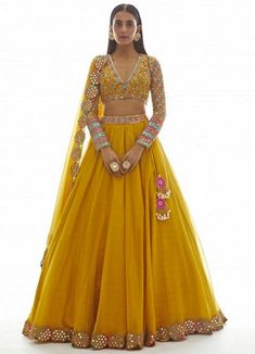 Step into elegance and radiate confidence with our Mustard Yellow Applique Lehenga Set. This exquisite ensemble features a beautifully hand-embroidered blouse adorned with stunning applique work. The skirt, crafted from luxurious silk organza, is enhanced with a mesmerizing mirror border that adds a touch of glamour. Complete the look with the matching dupatta, and you'll be the epitome of grace and style. Perfect for weddings, festivals, or any special occasion, this Lehenga Set from Vani is a true masterpiece that will make heads turn. Composition : Lehenga and Dupatta - Organza, Blouse - Georgette, Lining - Silk Blend Care: Dry Clean Only and Vacuum Storage This product can be customized for sleeves, length of blouse and neckline Delivery : 6-8 weeks as the product is hand crafted. Chec भारतीय दुल्हन संबंधी, Haldi Outfits, Haldi Outfit, Indian Outfits Lehenga, Yellow Lehenga, Indian Gowns Dresses, Ghagra Choli, Party Kleidung, Party Wear Lehenga