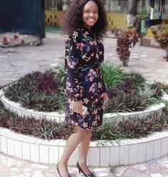 a woman standing in front of a flowered circle with her hand on her hip