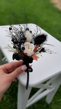 a person is holding a fake flower on a white table outside with grass and lawn in the background