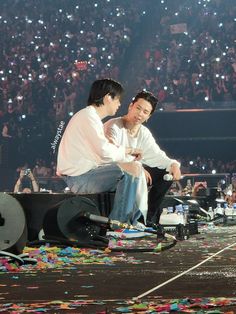 two men sitting on the ground with confetti all over them at a concert