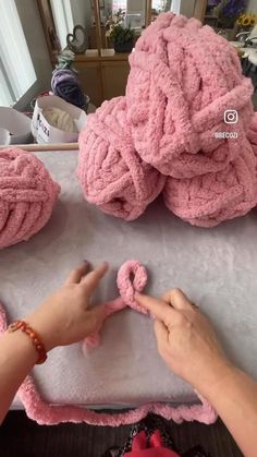 someone is making pink yarn balls on a table