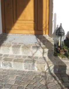 the front door is open and there are two lanterns on the stone steps next to it