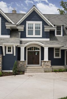 a blue house with white trim and stonework on the front door, windows, and steps