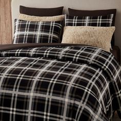 a black and white plaid comforter set on a bed with brown pillow shampoos