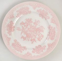 a pink and white plate with floral designs on the rim, against a white background