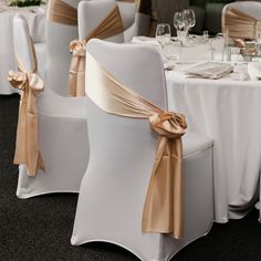 the chairs are decorated with gold sashes and champagne colored bowknots on them