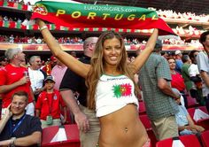 a woman holding up a portugal flag in the stands at a soccer game with other people watching