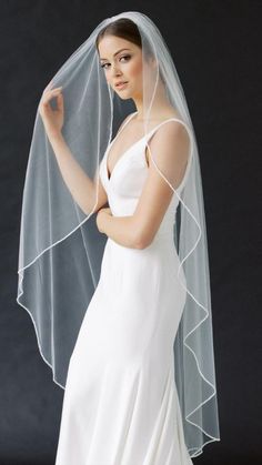 a woman in a white wedding dress with a veil on her head and one arm