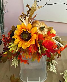 a vase filled with lots of different types of flowers and leaves on top of a table