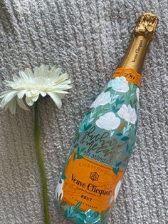 a bottle of champagne sitting next to a flower on a blanket with a white flower