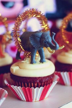 cupcakes with decorations and an elephant figurine sitting on top of them