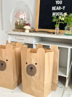 three brown paper bags with bears on them sitting on a table next to a plant