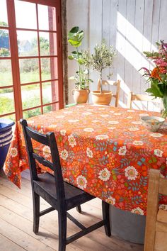 the table is covered with an orange flowered tablecloth and has potted plants on it