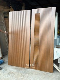 a woman standing next to two wooden doors in a room with wood slats on it