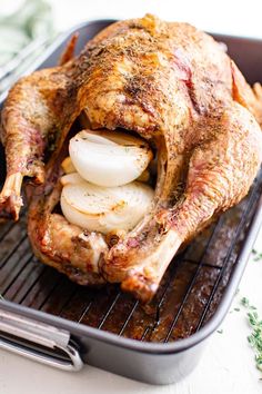 a roasting pan with a whole chicken on it and onions in the bottom half