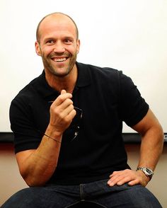 a man sitting in front of a whiteboard with his hands on his hips and smiling