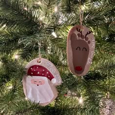 two ornaments hanging from a christmas tree decorated with santa claus and reindeer head decorations,