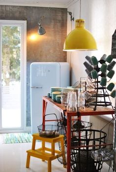 a kitchen area with a table, stools and lights hanging from the ceiling above it