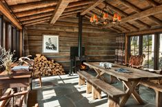 an old log cabin with wood burning in the fireplace and large wooden table surrounded by chairs